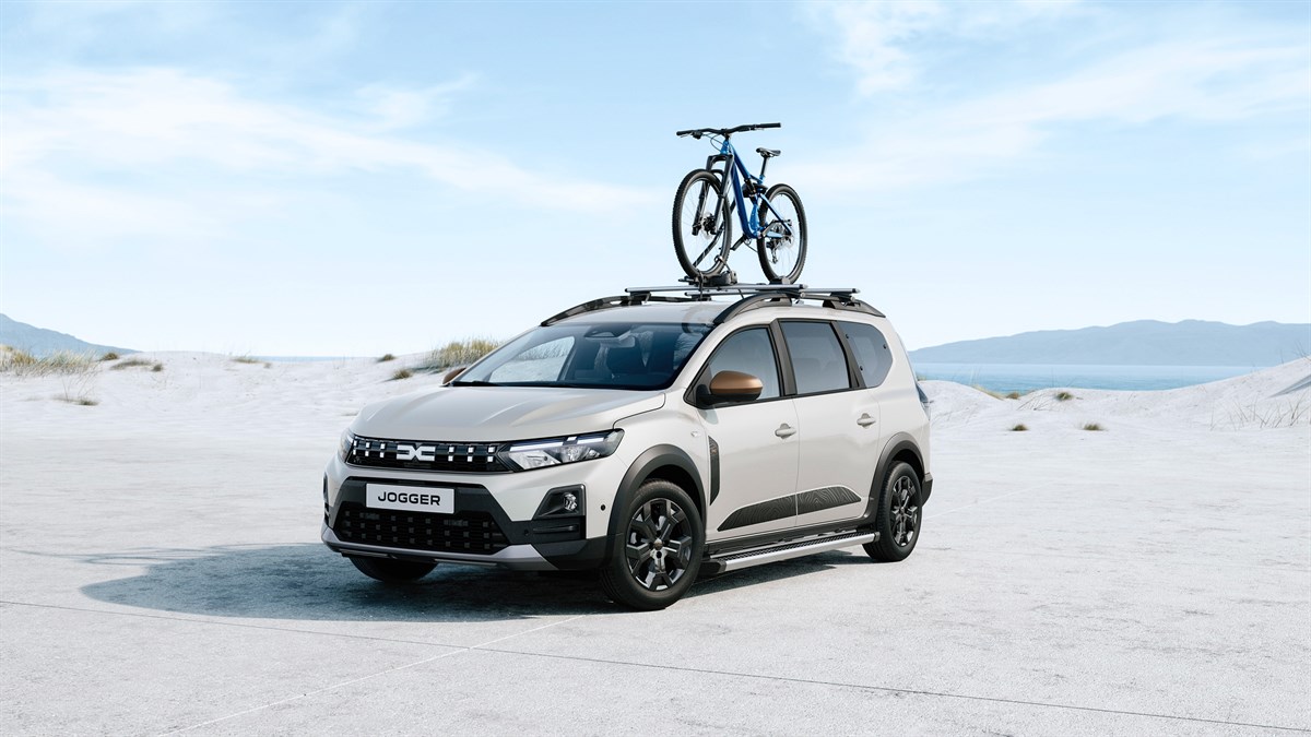Возило Dacia Jogger во отворен простор со велосипед прикачен на држачите на кровот.