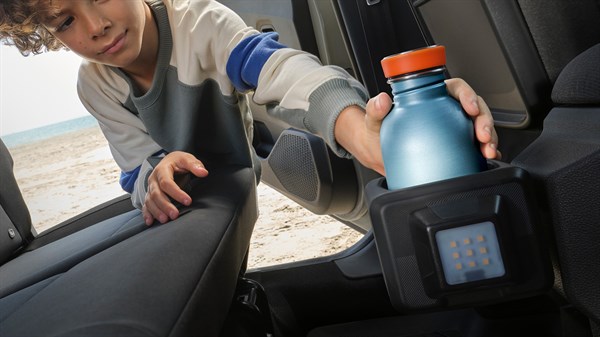 Дете седи на задното седиште на Dacia Jogger и става шише во држачот YouClip монтиран на страничните седишта.