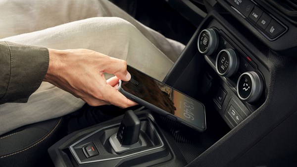 Рака поставува паметен телефон на вградениот безжичен полнач на Dacia Jogger, кој се наоѓа во централната конзола.