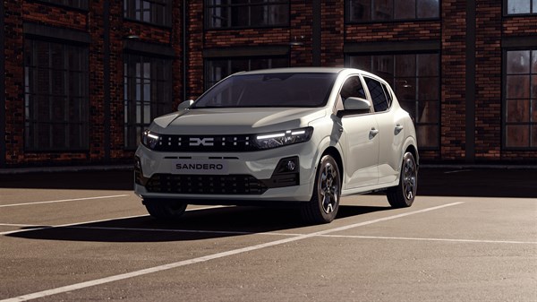 Возило Dacia Sandero фотографирано од напред на паркинг, со редизајнирана предна решетка и пикселизиран светлосен потпис.